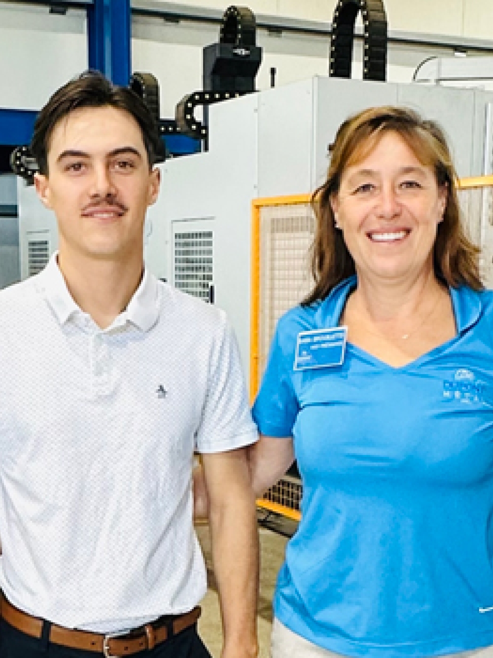 Quatre personnes debout dans un atelier industriel, posant devant de l’équipement de machinerie.