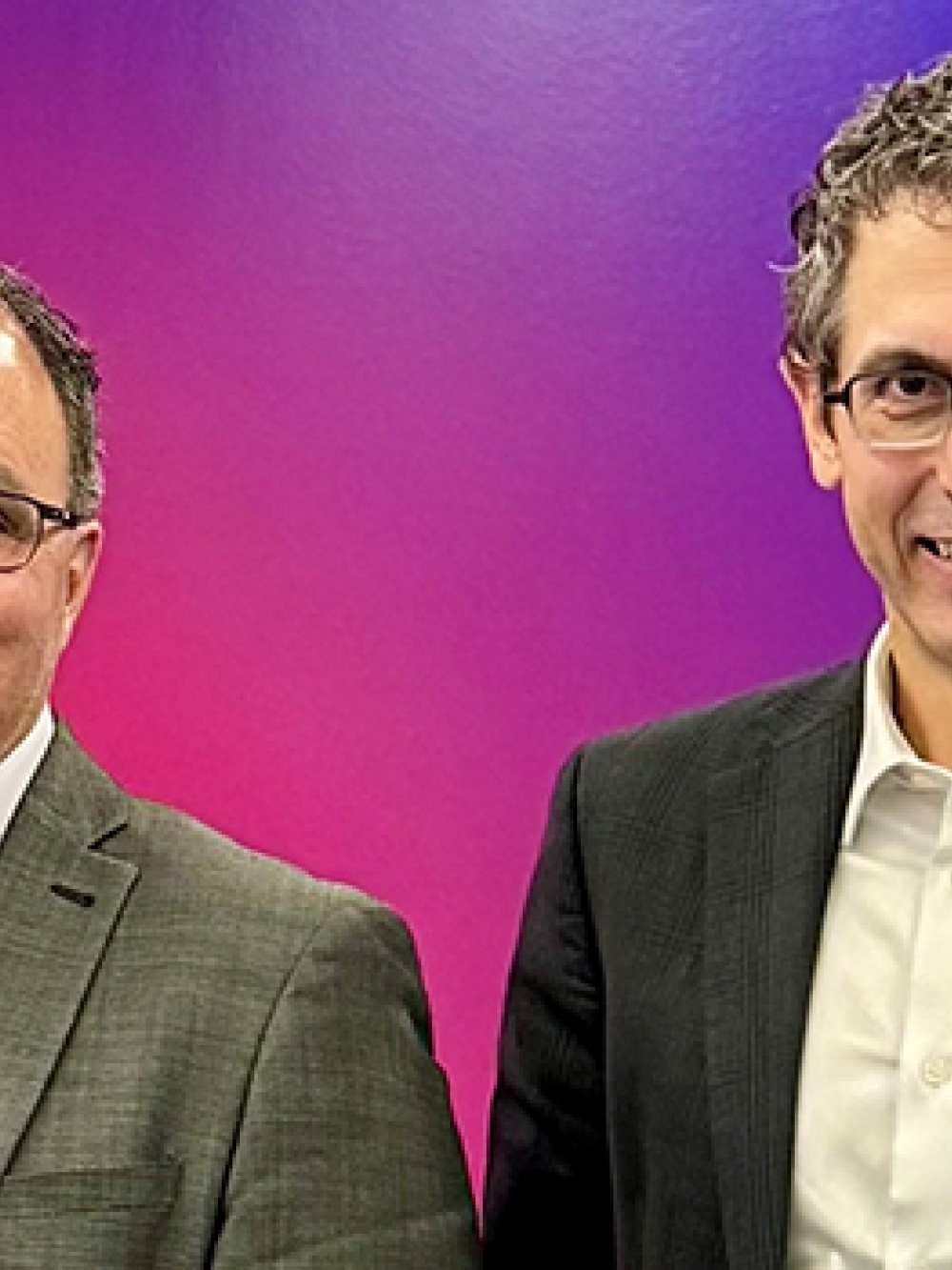 Deux personnes debout, vêtues de vestons professionnels.