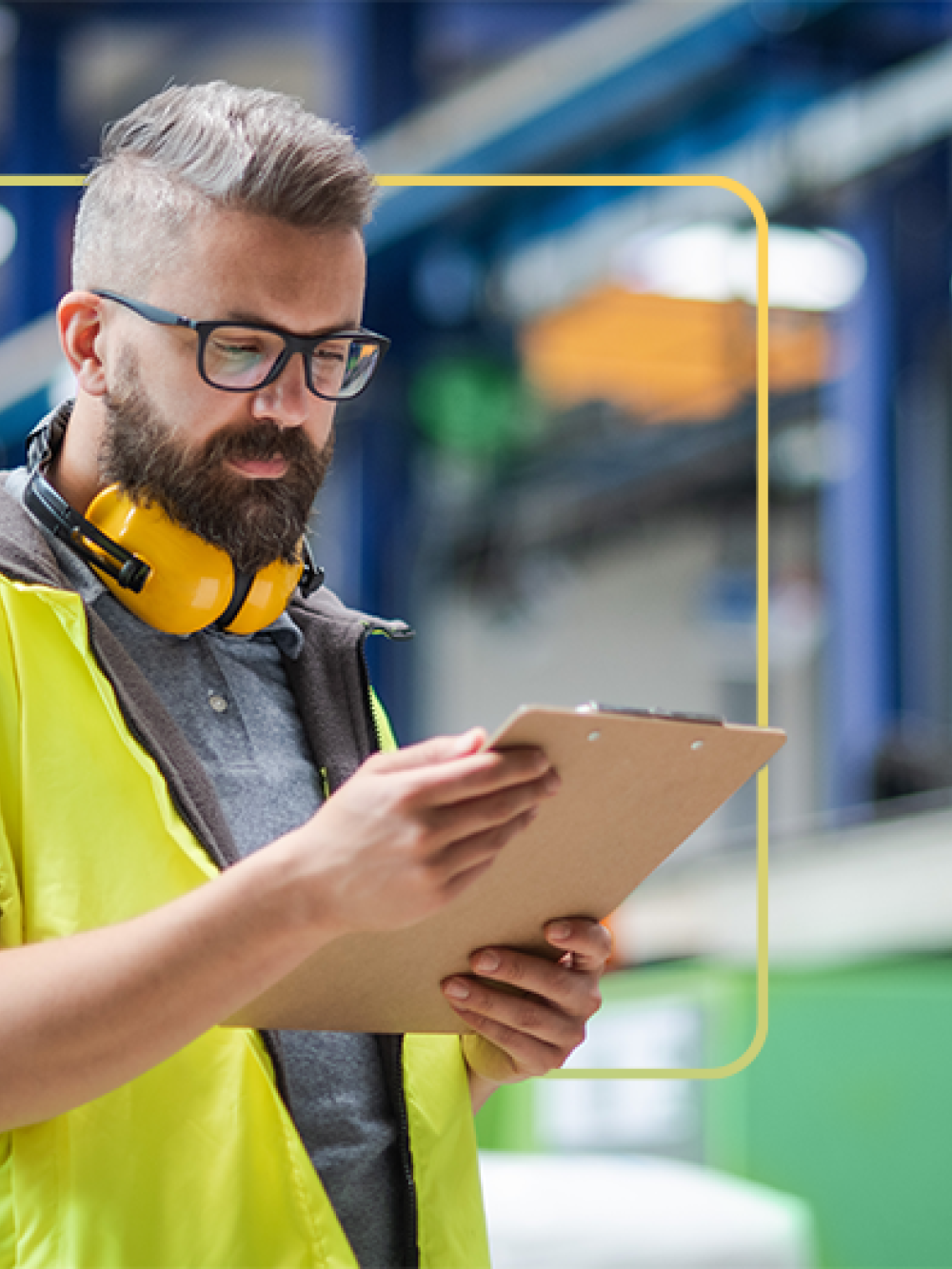 Personne portant un gilet de sécurité jaune tenant une tablette à pince dans un environnement industriel.