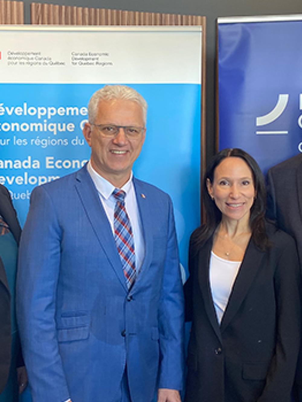 roupe de six personnes posant à l’intérieur devant des bannières gouvernementales, dont celles de Développement économique Canada et d’Investissement Québec.