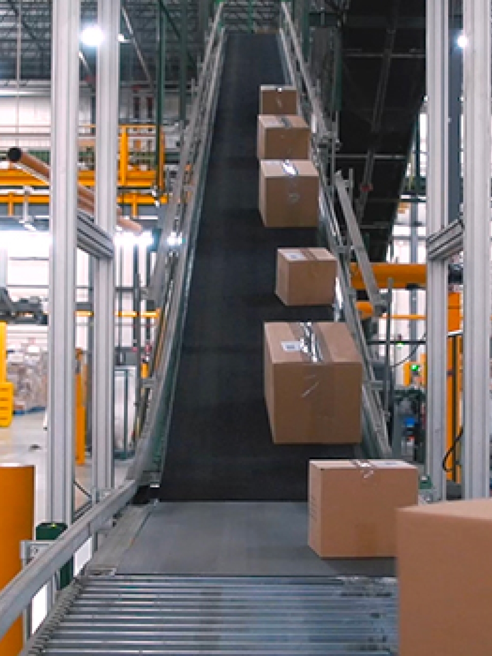 Convoyeur incliné transportant des cartons dans un entrepôt logistique moderne