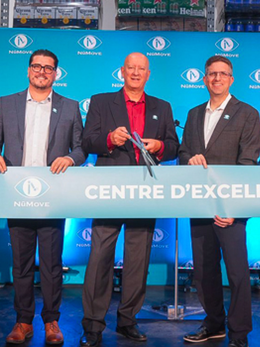 Groupe de personnes lors d’une cérémonie d’inauguration, tenant un large ruban turquoise portant l’inscription « Centre d’excellence », devant un fond aux couleurs de NuMove.