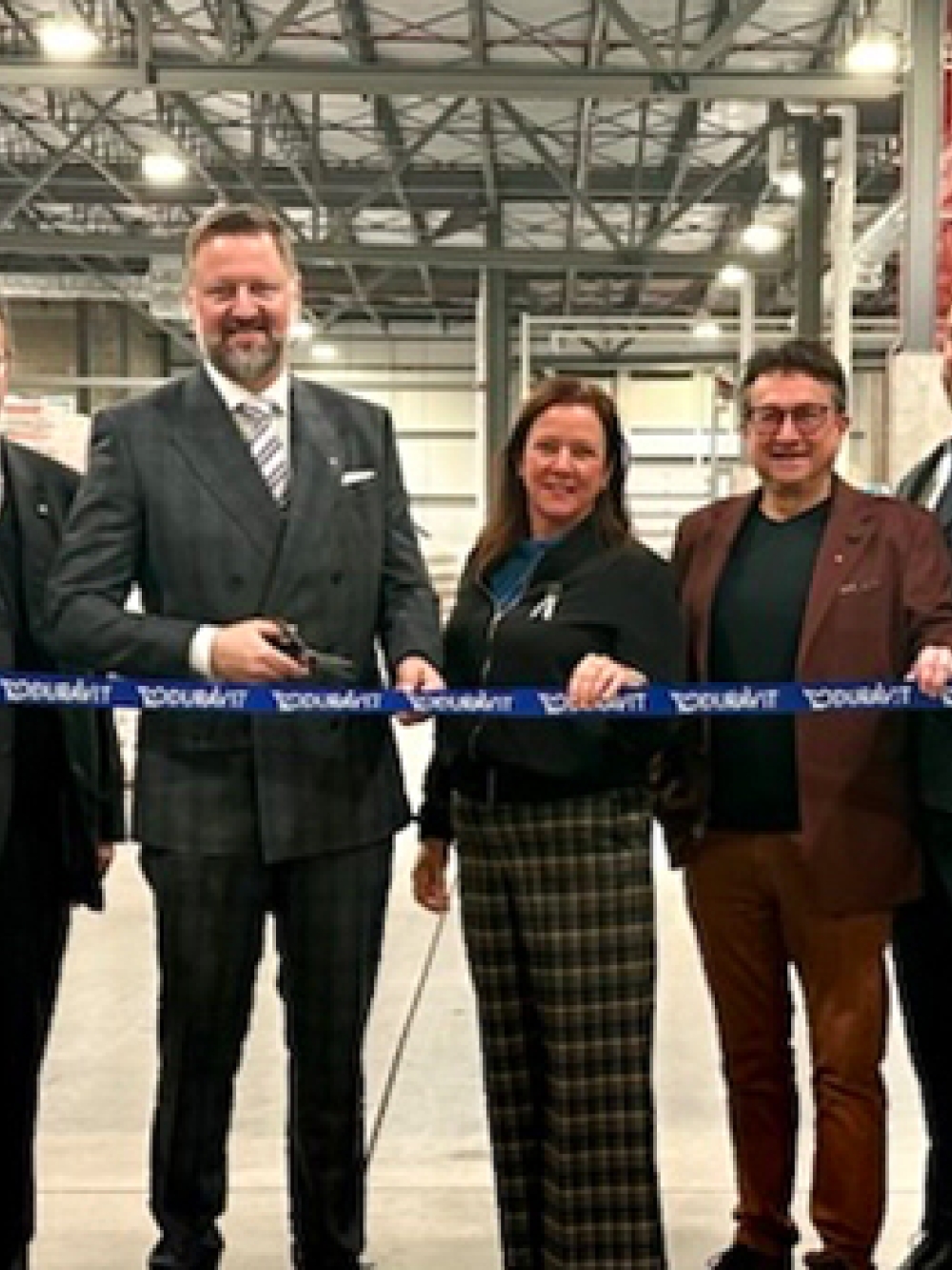 Groupe de personnes tenant un ruban bleu portant le nom « Duravit » lors d’une cérémonie d’inauguration à l’intérieur d’une usine.
