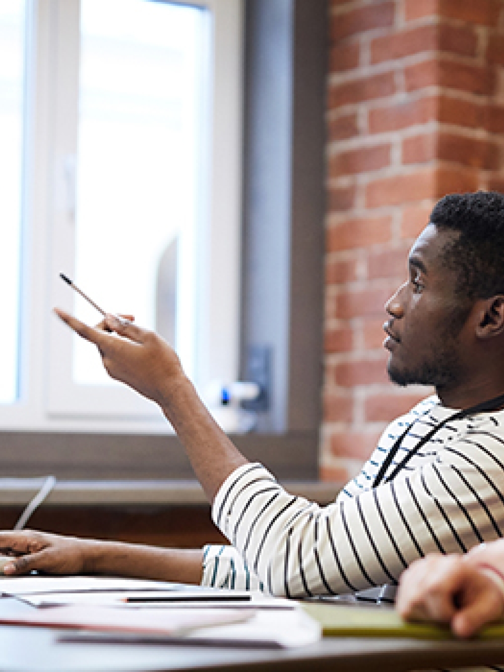 Trois personnes sont réunies autour d’une table dans un espace de travail en briques, discutant devant un écran d’ordinateur affichant du code.