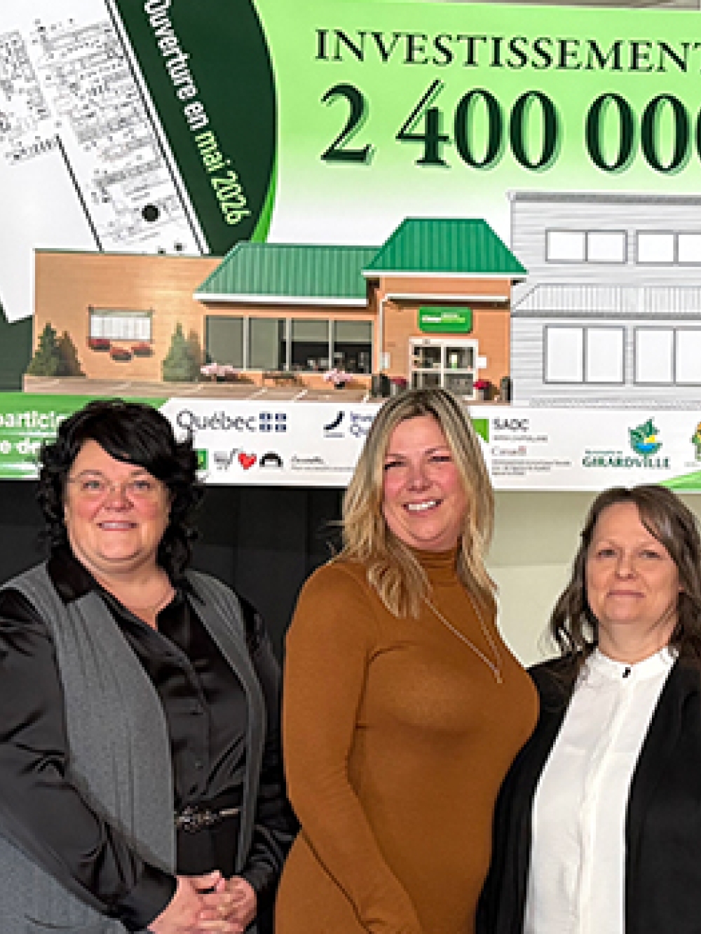 Cinq personnes posent devant un panneau annonçant un investissement de 2 400 000 $ pour un projet immobilier, accompagné d’un dessin architectural et de logos de partenaires.