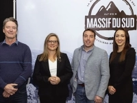 Quatre personnes debout devant une grande affiche de la Station touristique Massif‑du‑Sud.