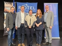 Groupe de personnes posant sur une scène devant des bannières du Riôtel et d’Investissement Québec lors d’un événement officiel.
